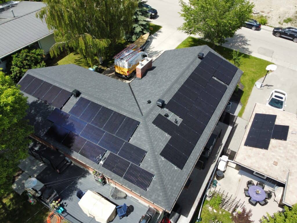 Solar panels being installed on a new asphalt shingle roof in Calgary